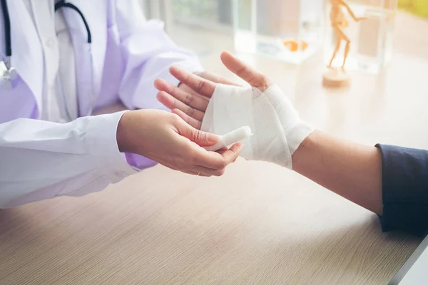 İlk yardım ve tedavi bilek yaralanma ve hastalıklar, Traumatologist hastanın, bir el bandaj kadın doktor ilgileniyor.