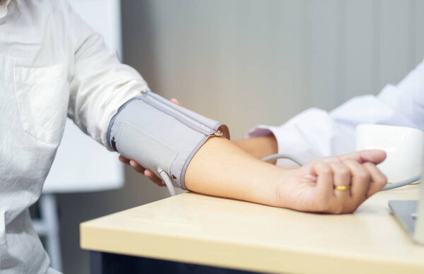 Doctor checking blood pressure of the patient, selective focus, Health care in clinic