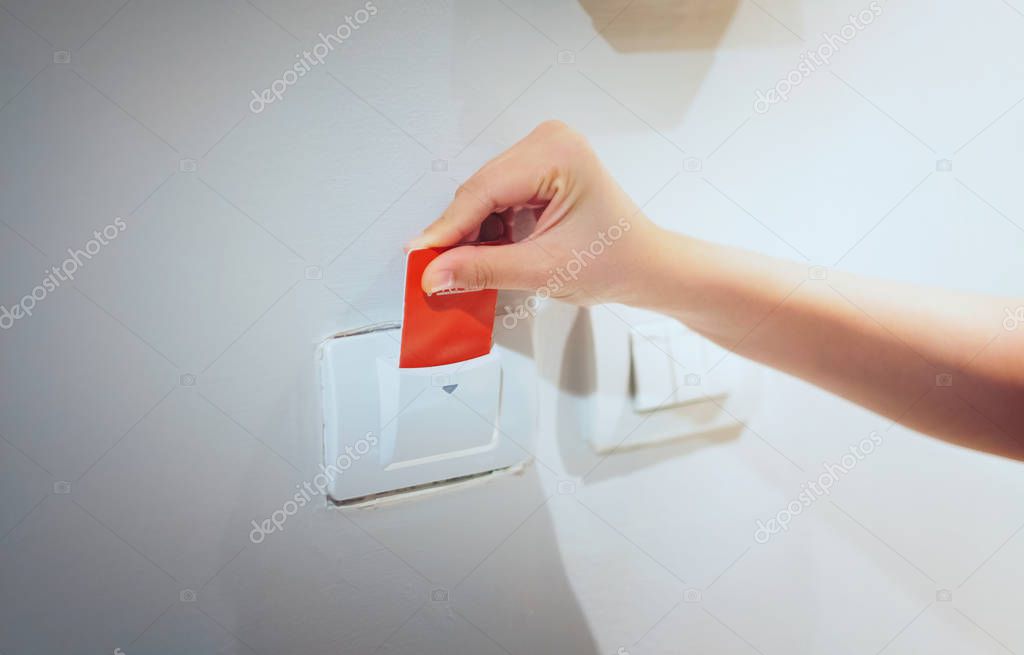 Closeup women hand insert key card to opening light electronic in hotel room.  Hotel room key card in electronic lock on the wall
