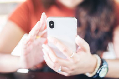 Kullanan bir akıllı telefon, rahat ev iç oturma ve modern smartphone aygıtı kullanarak genç hippi kız cep telefonu, sosyal ağ kavramı ile metin mesajı yazmaya eller kadın