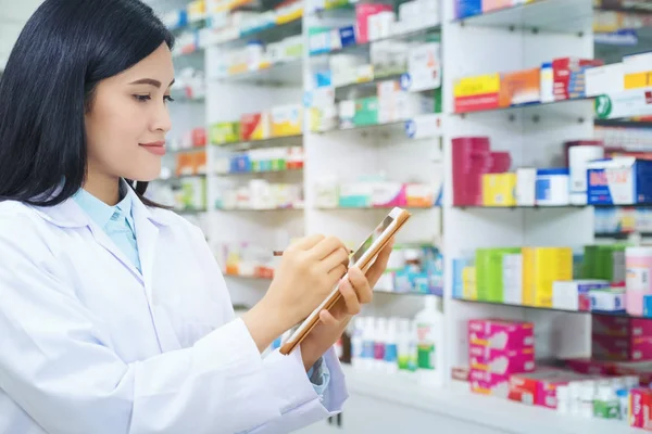 Pharmacist working with a tablet computer in the pharmacy holdin