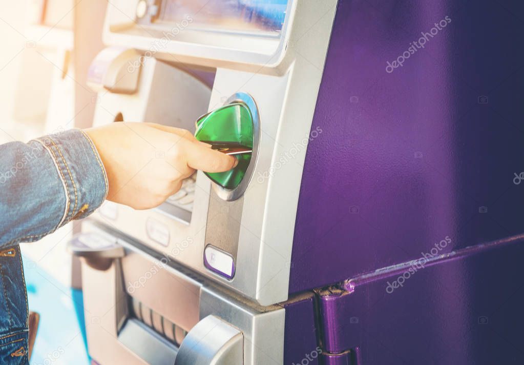 Women nand inserting ATM credit card into bank machine