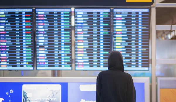 Widok z tyłu młodego mężczyzny na lotnisku w pobliżu rozkład lotów, Hacker — Zdjęcie stockowe