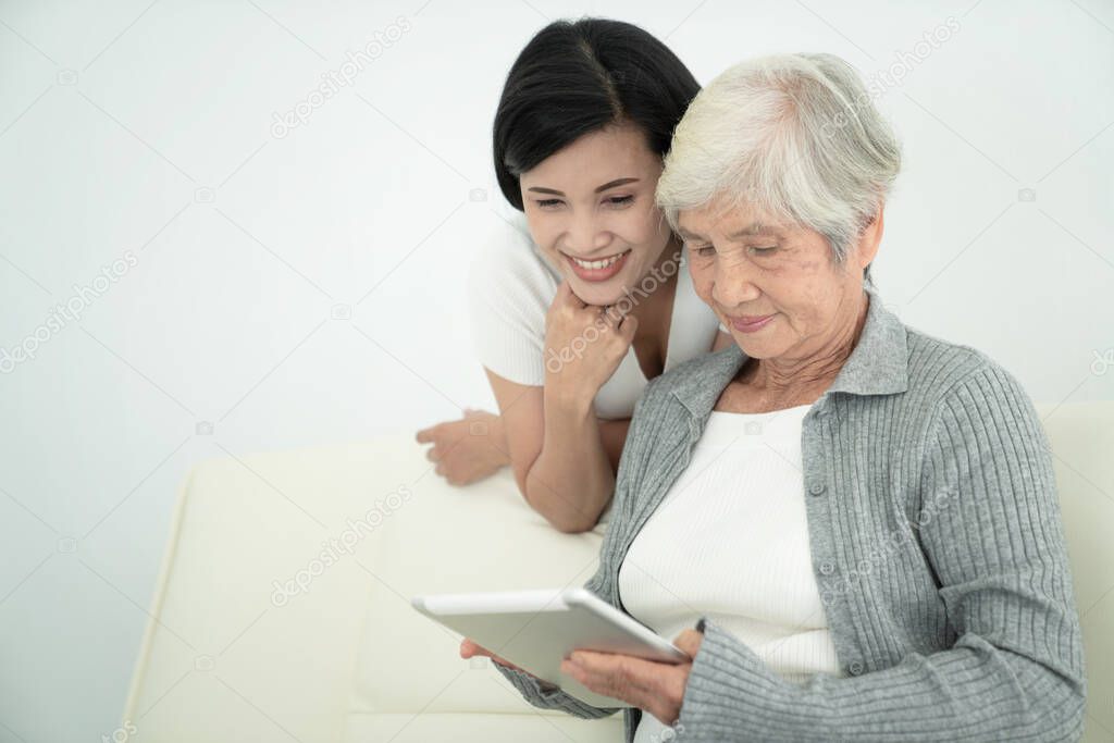 Ealry mother with daughter using digital tablet together at home. Smiling family looking at screen, shopping online