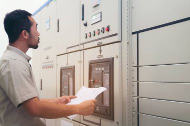 Elektrik mühendisi kontrol odasındaki elektrik dağıtım kabinesindeki voltajı ve testleri kontrol ediyor.