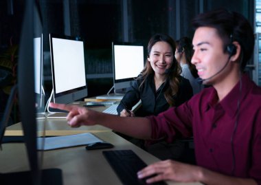 Taylandlı genç müşteri hizmetleri operatörleri gece vardiyasında çalışıyor.