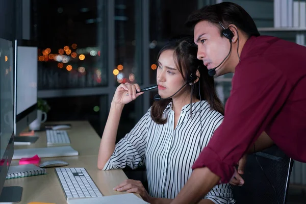 Young Thai Asian customer services care operators working night shift in call center for helping assistance client in workplace at night time