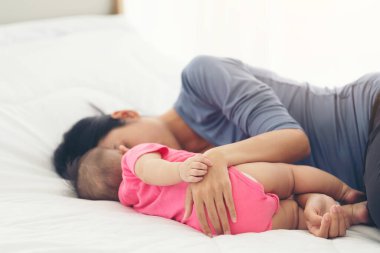 Annenin elinde uyuyan bir bebeğin eli. Yatağı kapat. Anne ve bebeği evde uyuyorlar.