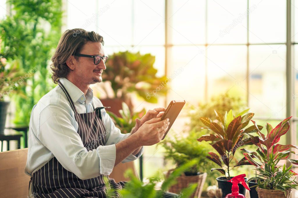 Man in casual outfit doing a hobby with happy and relax enjoy drinking coffee and using tablet for online social in greenhouse garden farm