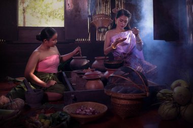 Geleneksel Tayland kıyafeti giyen Asyalı kadın geleneksel kültür ve geleneğe göre Ayutthaya, Tayland 'daki eski evde mutfakta yemek pişiriyor.