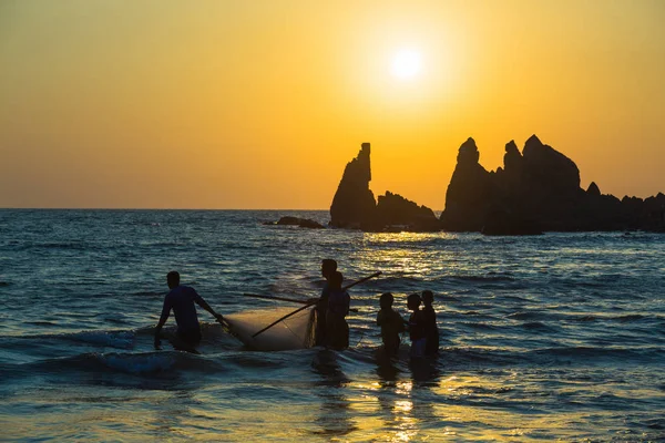 Arambol, March 6, 2017. Fishermen on a sunset background in western India. Goa