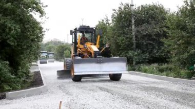Sınıf öğrencisi Ekskavatör yolda ezilmiş taş yaymak