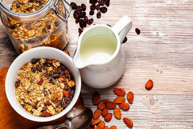 Kâsede müsli, kavanoz ve sütle ahşap masada. Sağlıklı kahvaltı kompozisyonu. Kopyanı yerleştir