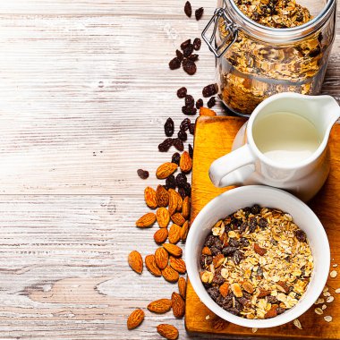 Kâsede müsli, kavanoz ve sütle ahşap masada. Sağlıklı kahvaltı kompozisyonu. Kopyanı yerleştir