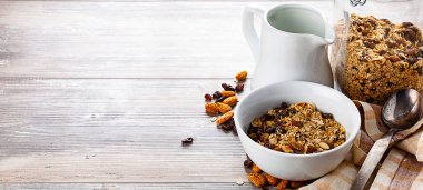 Kâsede müsli, kavanoz ve sütle ahşap masada. Sağlıklı kahvaltı kompozisyonu. Kopyanı yerleştir