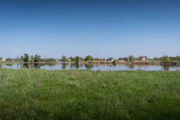 Красивый сельский пейзаж - это зеленая горка, озеро и маленькая деревня — стоковое фото