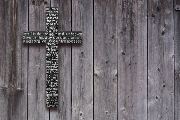 Black wooden cross with the Lords prayer on the old  dark brown wooden  plank background — Stock Photo, Image