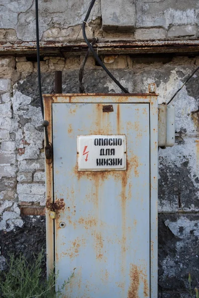 Vieille porte rouillée derrière un panneau d'avertissement dans un bâtiment abandonné en ruine — Photo