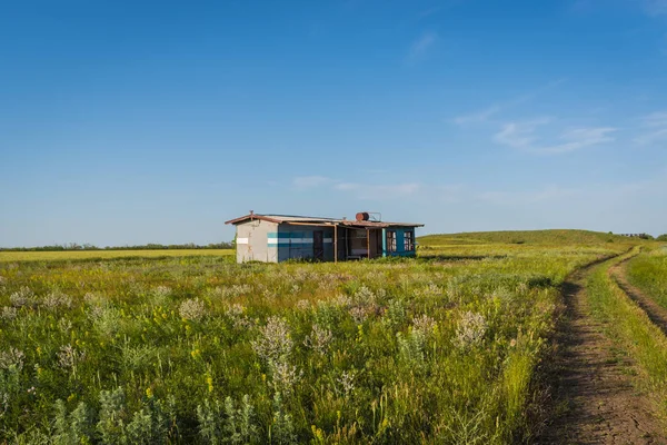 Casa de pintores abandonados en un campo verde sobre un fondo azul del cielo — Foto de Stock