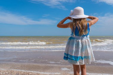 Mavi gökyüzü arka plan üzerinde deniz plajında beyaz şapkalı kız