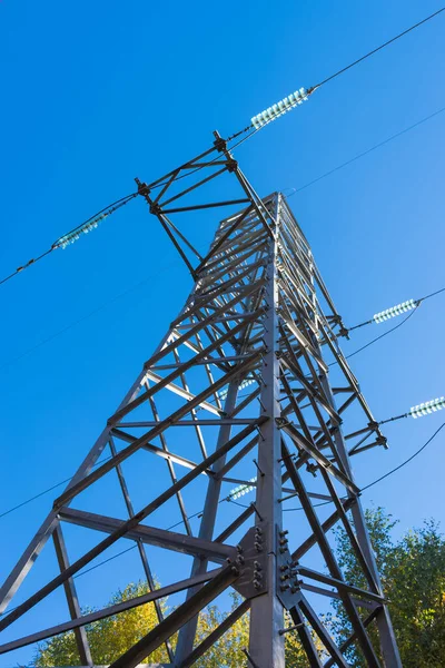 High voltage tower, power lines on blue sky background. Bottom view