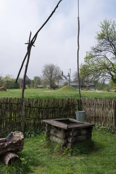 Tradicional pozo de madera ucraniano en el patio con una valla de madera — Foto de Stock