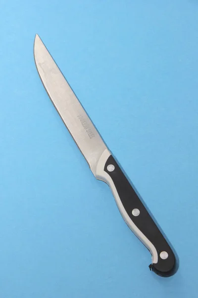 The knife rests on a blue surface, single subject