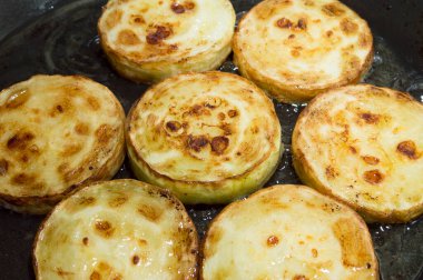 Taze balkabağını kızartırken tavada doğranmış daireler. Kavunla yemek pişirmek..