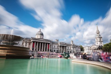 Turist ve yerli gruplar Trafalgar Meydanı 'ndaki Ulusal Galeri' nin ana girişinde güneşin tadını çıkarıyorlar. Galeri, Batı Avrupa 'nın ulusal resim koleksiyonuna ev sahipliği yapmaktadır. Uzun pozlama.