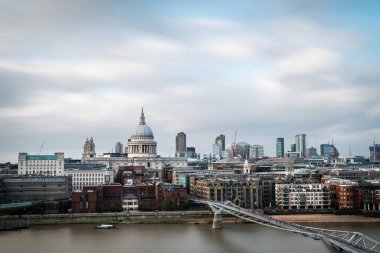St. Pauls Katedrali 'nin kubbesi ve bulutlu bir yaz gününde Thames nehrinin güney kıyısından görülen Londra şehrinin modern gökdelenleri. Uzun pozlama.