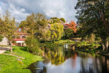 Sonbahar yaprakları Galiçya 'nın Allariz köyündeki suya yansıyor..