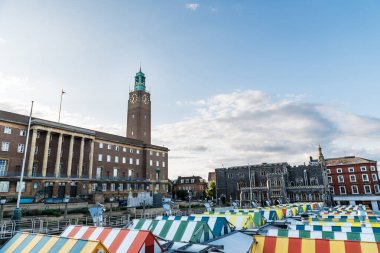 Norwich Pazarı 'ndaki renkli çatıların geniş açılı görüntüsü, arka planda ortaçağ loncası, ilk olarak şehir hükümetinin merkezi olarak inşa edilmiş tarihi bir yapı..