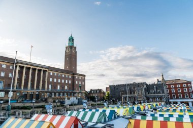 Wide-angle view of the colourful rooftops on Norwich Market, with the medieval Guildhall in the background, a historic construction originally built to serve as the seat of the city government. clipart