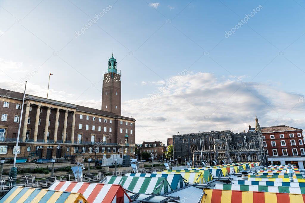 Wide-angle view of the colourful rooftops on Norwich Market, with the medieval Guildhall in the background, a historic construction originally built to serve as the seat of the city government.