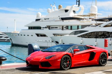 Marbella, İspanya - 13 Ekim 2016: Marbella, İspanya 'da Costa del Sol' da Puerto Jose Banus marinasında demirlemiş lüks yatların yanında park etmiş kırmızı bir süper spor arabanın (Lamborghini) ön görüntüsü.
