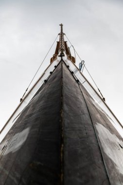 Bulutlu bir gökyüzüne karşı ahşap, lüks bir yelkenlinin pruvasının alçak açısı..