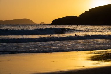 Altın gün batımı İspanya 'nın Galiçya kentindeki ıssız bir sahilde sığ sulara yansıyor..