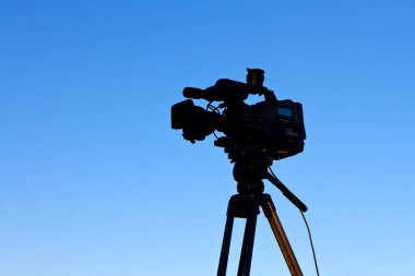 Mavi gökyüzüne karşı TV kamerası ve video tripod. (yapım, kamera, video)