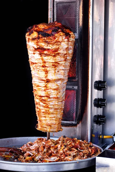 Doner kebab on it's special bbq set with tray of sliced meat seen from above