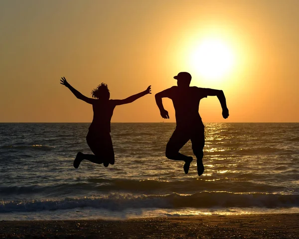Dva Přátelé Skákání Pláži Během Východu Slunce — Stock fotografie