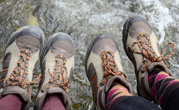 Legs of hikers with same boots  hanging