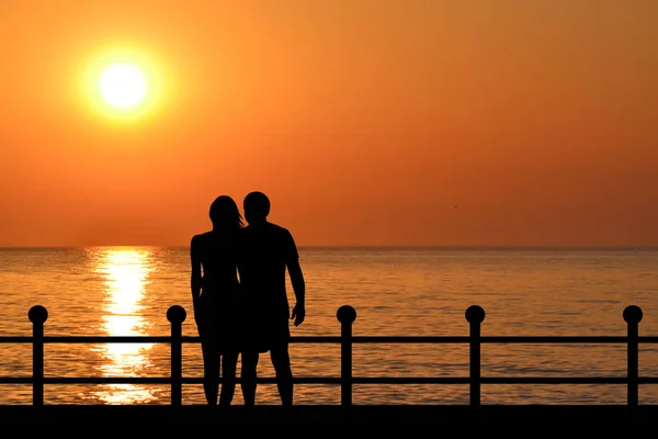 Silhouette of couple on the waterfront at sunrise — Stock Photo, Image