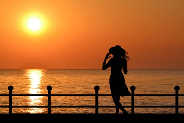 Silueta de una mujer en el paseo marítimo al amanecer —  Fotos de Stock