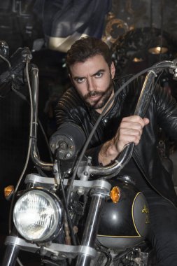Motorcu moda kavramı. Kapalı poz zarif genç yakışıklı adam motorcu portresi.