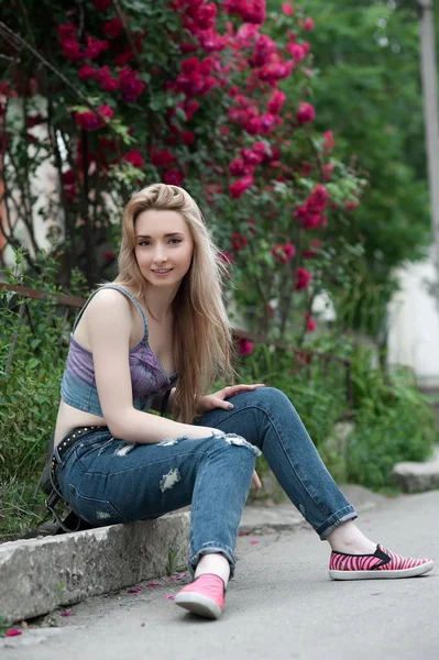 Beautiful sexy young blond woman in torn jeans posing on the streets of the old town