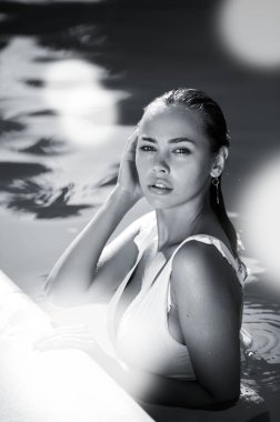 Havuzda beyaz mayo giymiş güzel bir kadın.