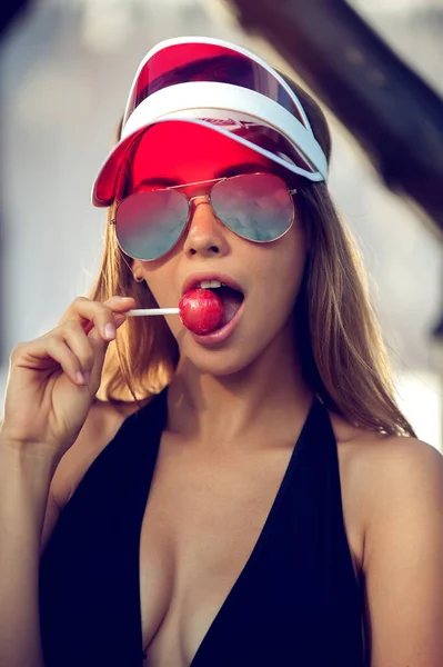 Portrait of beautiful woman in sun visor with lollipop