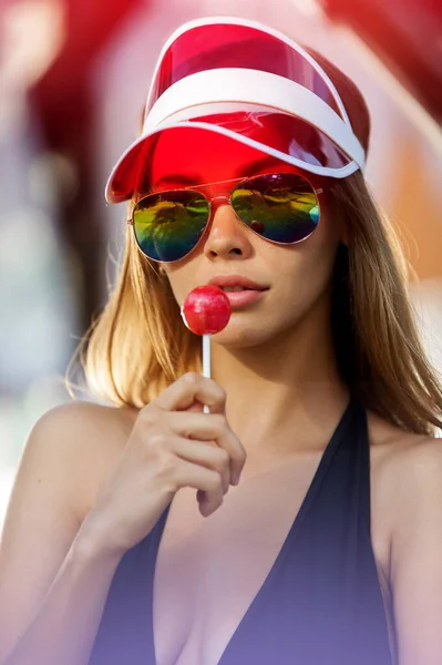 Portrait of beautiful woman in sun visor with lollipop