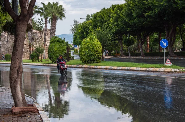 Yağmurdan sonra kaygan bir yolda motosikletli bir adam.