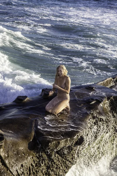 海沿いの岩の上のガウンの美しいブロンド — ストック写真